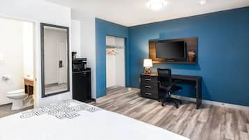 Quarto moderno com cama, escrivaninha, cadeira, televisão e guarda-roupa.