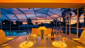 Une table dressée pour un dîner à deux, avec une bouteille de champagne, des verres et un vase de fleurs.