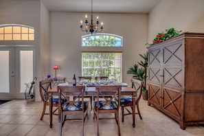 Zona pranzo con tavolo e sedie in legno, un lampadario e un armadio con piante.
