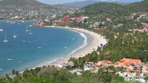 A coastal town with a beach, boats, and buildings. - La Casa Que Ve al Mar te da la bienvenida en 2026! (Zihuatanejo)