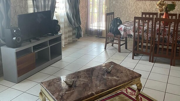 Un salon équipé d’un téléviseur, d’un meuble de rangement pour les appareils multimédias et d’un coin repas avec une table et des chaises.
