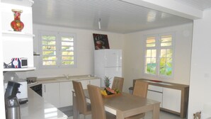 Une cuisine moderne avec des meubles blancs, une table à manger avec des chaises, un réfrigérateur et un four à micro-ondes.