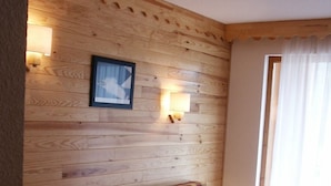 Une pièce en bois avec un canapé, deux lampes fixées au mur, un tableau encadré et une fenêtre avec des rideaux.