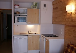 Una cocina compacta equipada con lavavajillas, microondas, estufa y pileta.