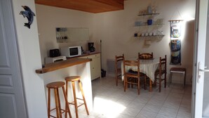 Una cocina compacta con microondas, cafetera y taburetes de madera.