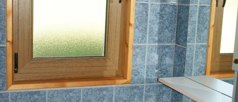 A bathroom with a wooden medicine cabinet, a white sink, and blue-tiled walls.