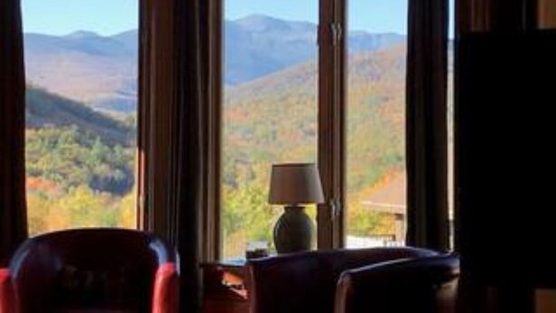 A room with a large window offering a view of a mountainous landscape.
