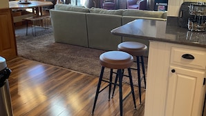 A cozy kitchen with wooden flooring, a dining area with a sofa, and a bar stool.
