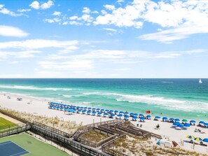 A beach with blue umbrellas and a sandy shore. - 604- Welcome to the Beach! Relaxation and spectacular views await! (Destin)