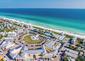 Eine Vogelperspektive einer Küstenstadt mit einem zentralen Platz, Strand und verschiedenen Gebäuden, darunter ein markantes Hotel mit Kuppel.