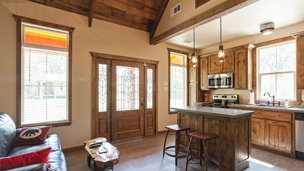 Una cocina amplia con armarios de madera, una isla central con taburetes y un gran ventanal que proporciona luz natural.