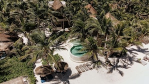 An aerial view of a resort with a central pool surrounded by palm trees and thatched-roof structures. - Casa Bonita ~ Mahayana, Eclectic Treehouse in the Heart of Tulum Beach (Tulum)