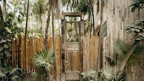 A rustic wooden door surrounded by bamboo fencing and tropical plants. - Casa Bonita ~ Mahayana, Eclectic Treehouse in the Heart of Tulum Beach (Tulum)