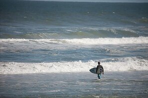 A person carrying a surfboard walking in the ocean. - 502 - Panoramic View to the East and South (New Smyrna Beach)