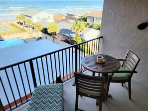 A balcony with a view of the ocean, a pool, and a table with chairs. - 502 - Panoramic View to the East and South (New Smyrna Beach)