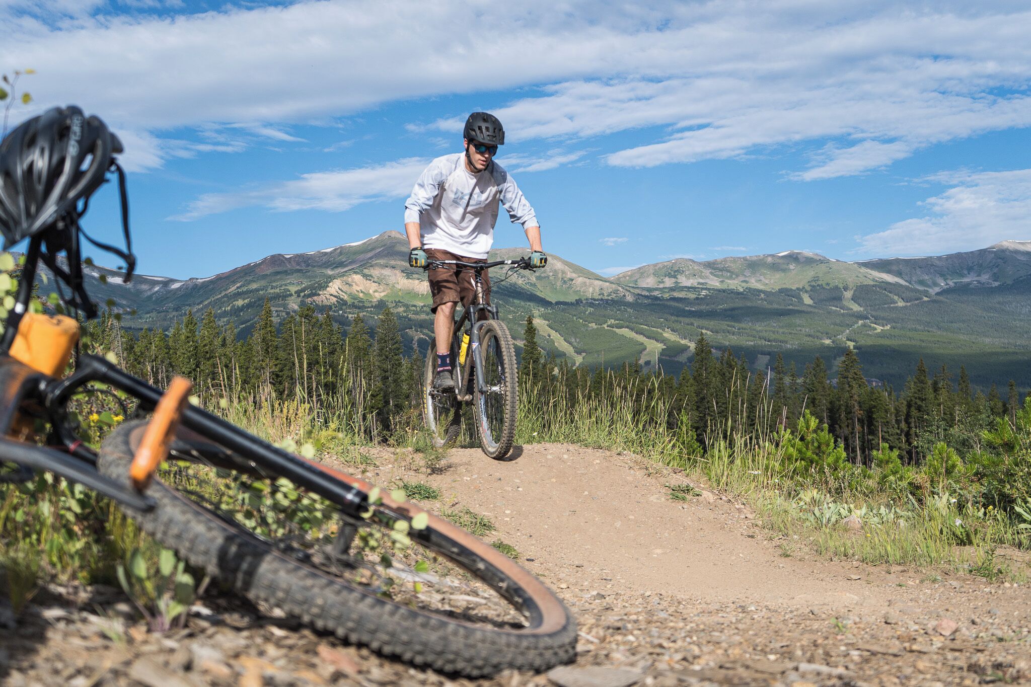 A mountain biker on a dirt trail with a scenic mountain backdrop.