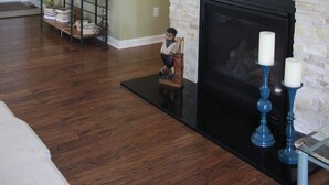 Una sala de estar con chimenea, televisor montado y piso de madera.