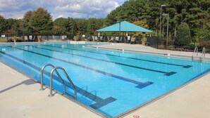 Una piscina con agua cristalina azul, rodeada por una cerca y protegida por un toldo azul.
