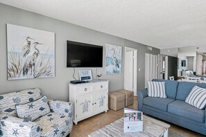 A living room with a sofa, a television, and artwork on the walls. - Sand Castle I 401 - GULF FRONT WRAP BALCONY Condo! (Indian Shores)