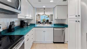 A modern kitchen with white cabinets, a black stove, and a teal countertop.