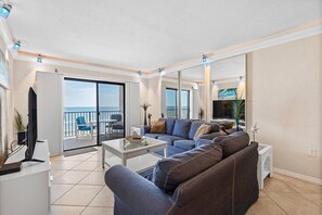 Una sala de estar con sofá, mesa de centro y vista al mar a través de un ventanal corredera.
