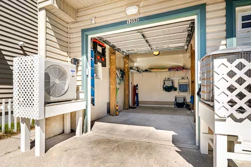 A garage entrance with a white door, a fan, and a ladder.