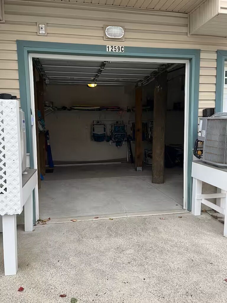A garage with a number 1259C on the door, a fan on the ceiling, and a white bench to the right.