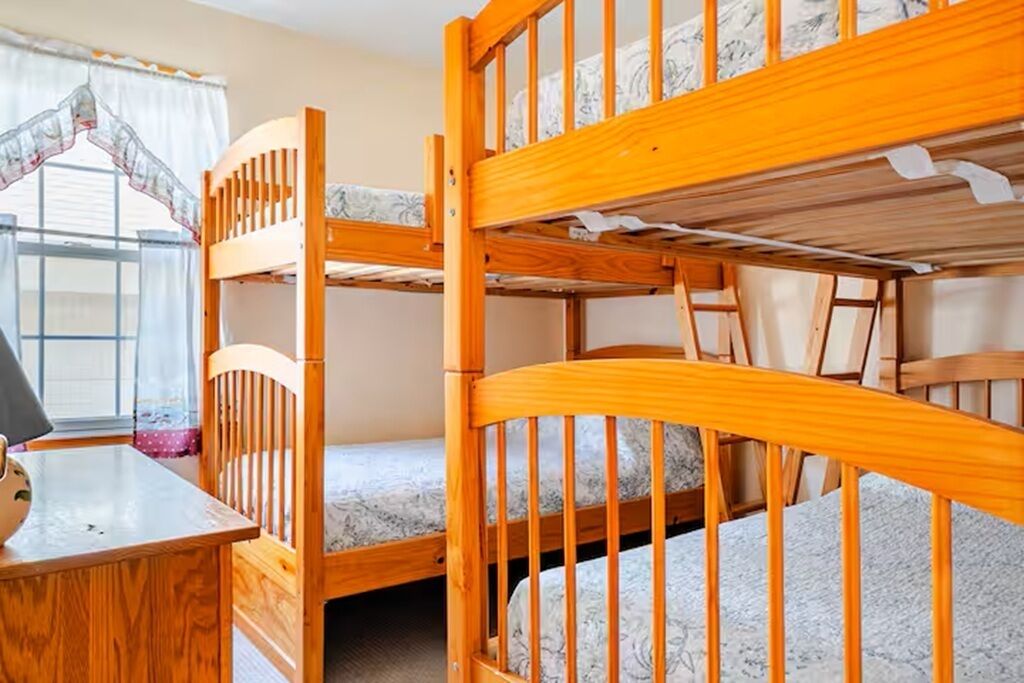 Habitación con literas, un escritorio de madera y una ventana con cortinas.