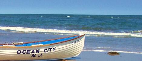 A boat named "Ocean City" on a sandy beach with the ocean in the background.