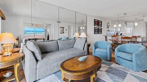 Un salon comprenant un canapé, des fauteuils, une table basse et un coin repas avec une table et des chaises.