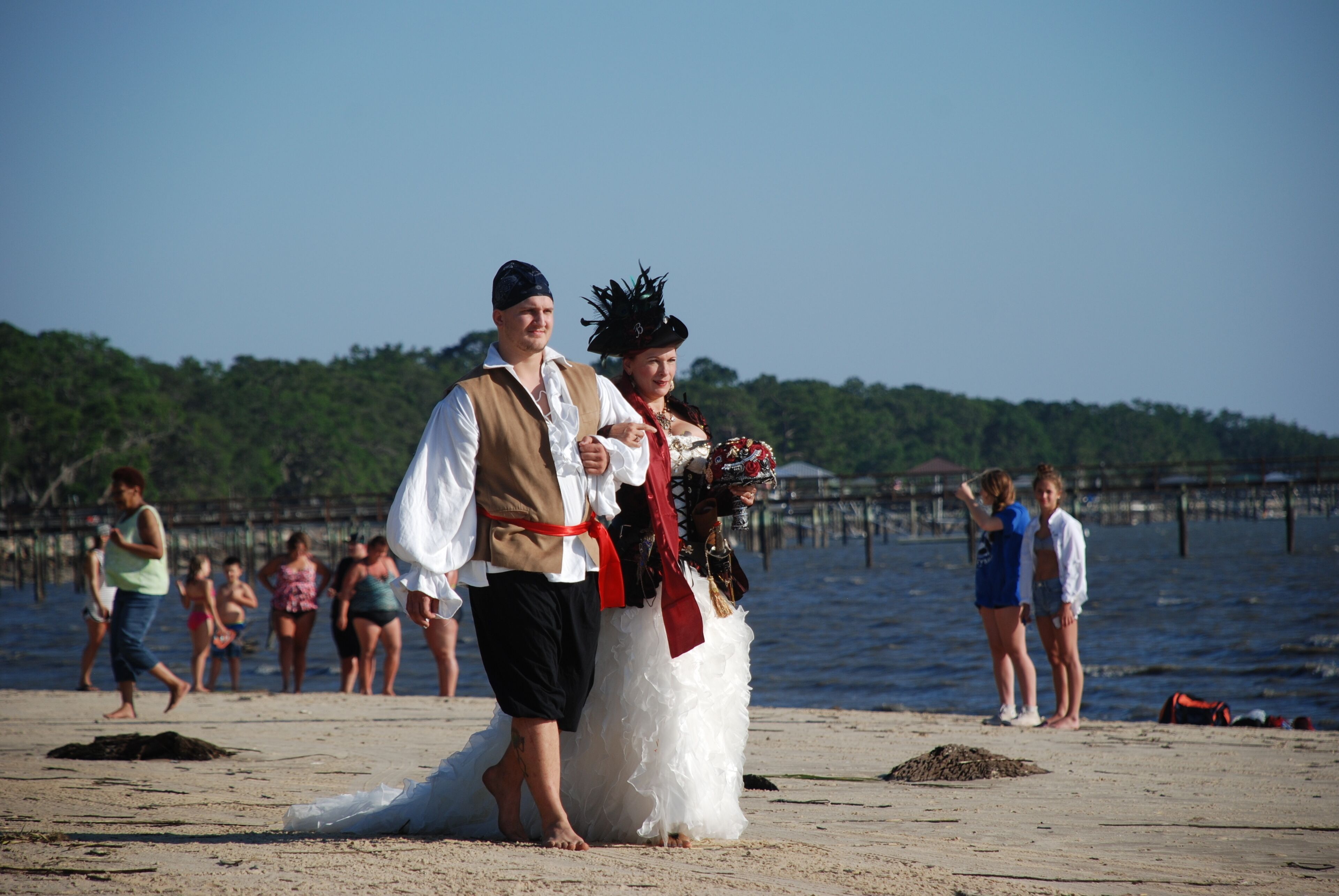 Una boda en la playa con una novia y un novio vestidos con traje de época.