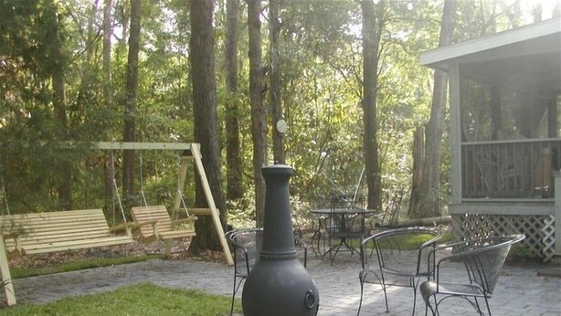 Eine Terrasse mit einem großen schwarzen Herd, Sitzgelegenheiten im Freien und einer Schaukel.