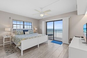 Quarto com cama, escrivaninha, ventilador de teto, janela e varanda com vista.