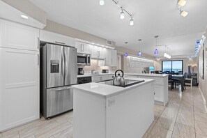 A modern kitchen with stainless steel appliances, a central island, and pendant lighting.