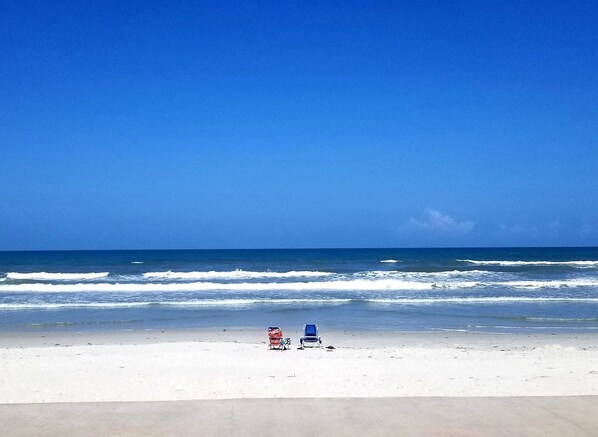 Una playa con dos sillas y una bicicleta.