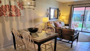 Un comedor con una mesa de vidrio, sillas blancas y un banco de madera oscura.