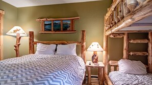 Ein rustikaler Holzraum mit einem großen Bett, zwei Nachttischen mit Lampen und einem kleinen Fenster mit einem Gemälde.