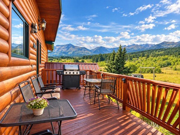 A wooden deck with a grill, seating, and a table with flowers.