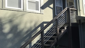 Ein Wohnhaus mit Treppe zum zweiten Stock, einem Backstein-Schornstein und einem kleinen Außenpflanzgefäß mit Pflanzen.