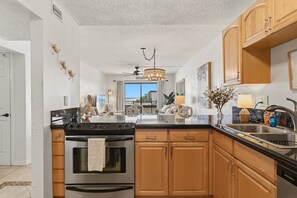 Una cocina moderna con una isla central, armarios de madera y electrodomésticos de acero inoxidable, con vistas al exterior.