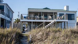 Et moderne sommerhus ved stranden med en overdækket terrasse og udendørs siddeplads.