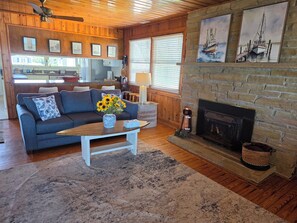 Un salon chaleureux avec une cheminée, un plancher en bois, un canapé et une table basse décorée de tournesols.