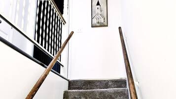 Una escalera con barandillas de madera y un cuadro de una iglesia en la pared.