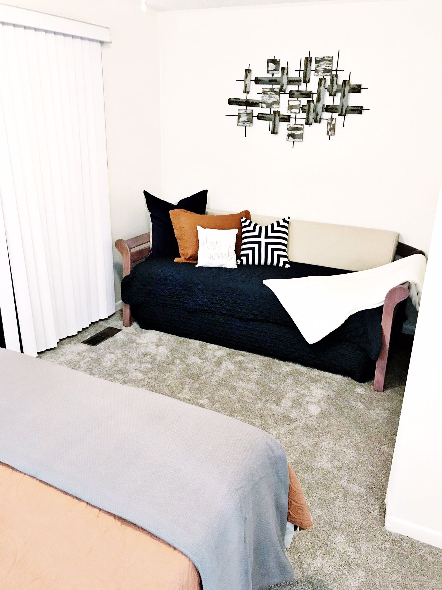 A room with a bed, a sofa, and a wall art piece.