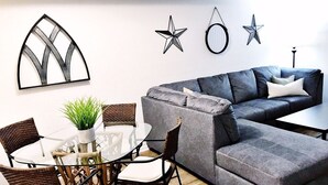 A living room with a grey sectional sofa, a round glass coffee table, wicker chairs, and a potted plant. - 🌟Updated Fairfield Glade Condo 🌟w/King Size bed, pet friendly, Wifi, & more! (Crossville)