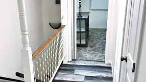 A staircase with a white railing and a wooden handrail, leading to a room with a lamp and a window. - 🌟Updated Fairfield Glade Condo 🌟w/King Size bed, pet friendly, Wifi, & more! (Crossville)