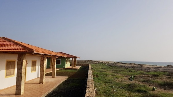 Une rangée de bâtiments avec des toits en tuiles, un chemin pavé et une zone herbeuse menant à la plage.