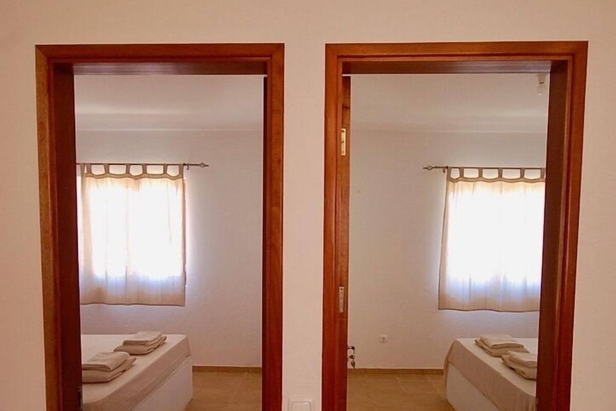 Une vue en miroir d’une chambre à coucher avec un lit, des rideaux et un sol carrelé.
