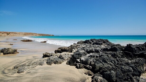 Uma praia com formações rochosas e águas azul-claras.