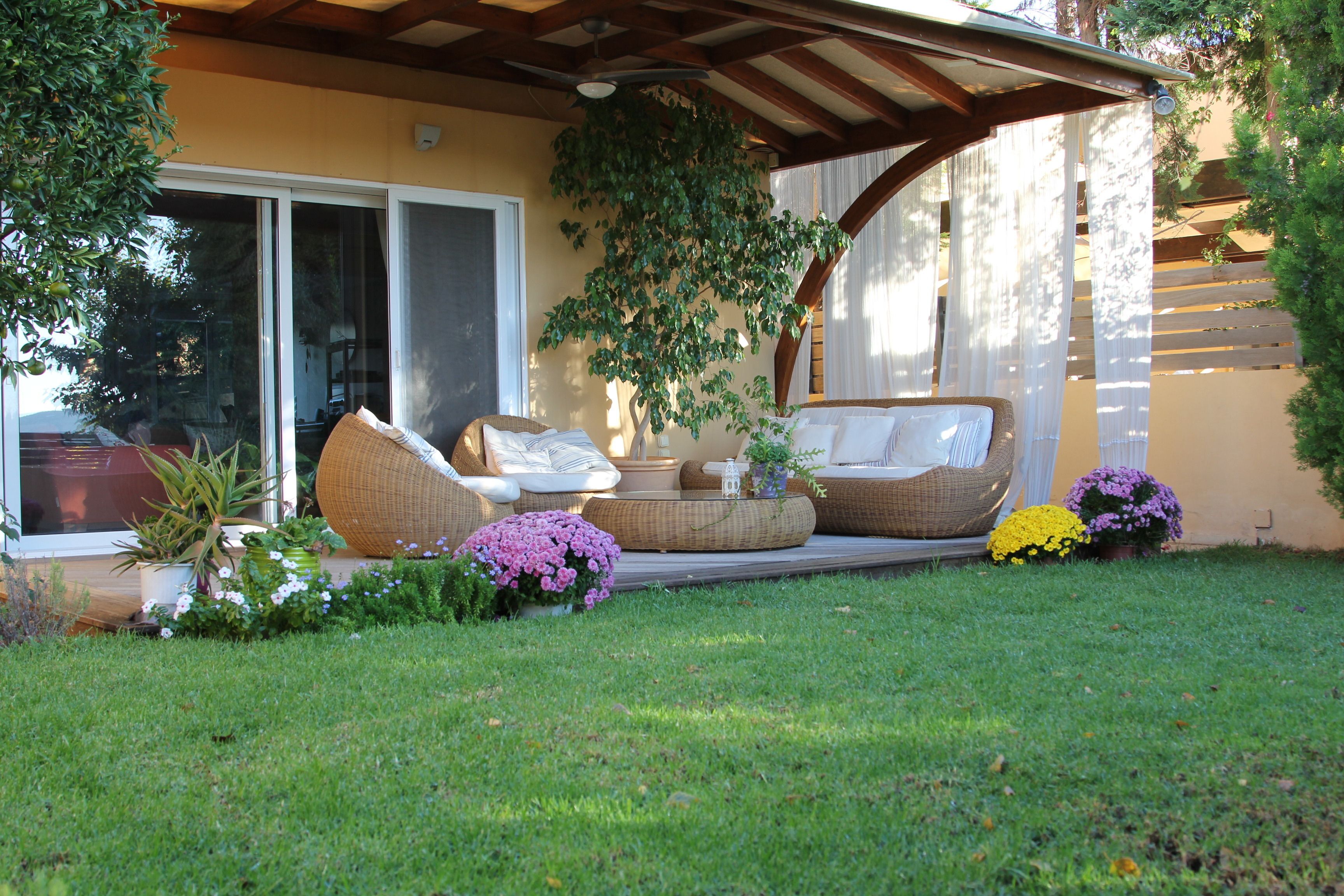 A covered outdoor seating area with wicker furniture and potted plants.